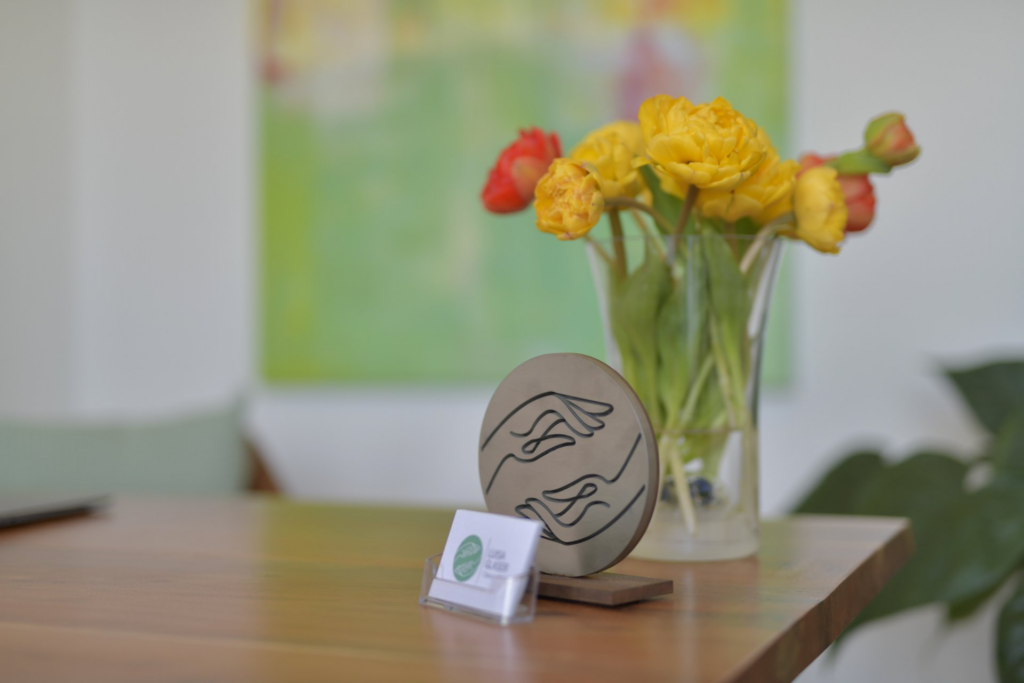 Empfang mit gelben Blumen und dem Holzschild mit dem Praxislogo